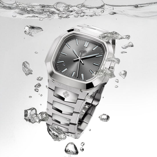 Silver automatic watch with a gray dial surrounded by water droplets